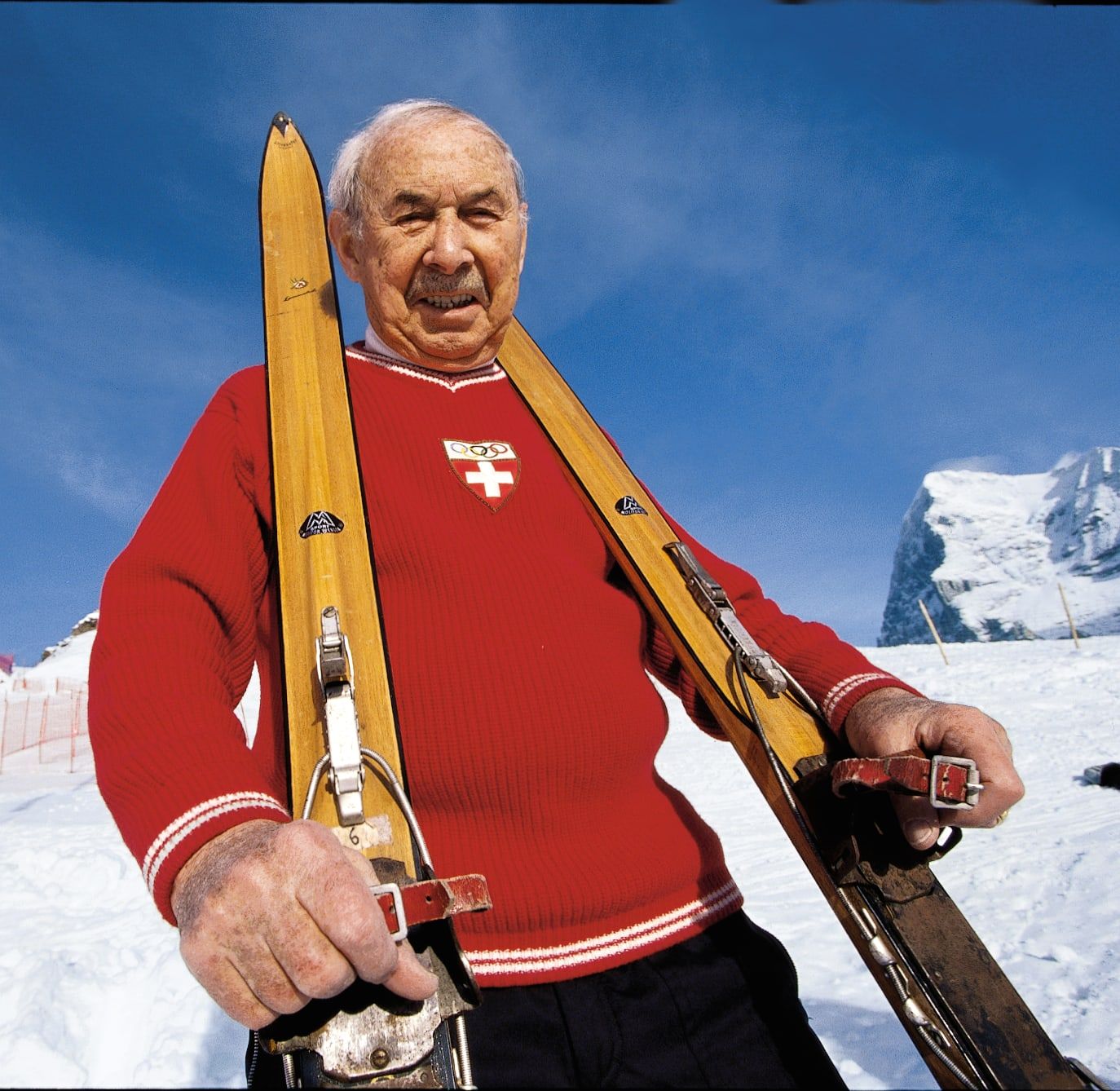 Wengener Skipionier mit Holzski und rotem Schweizer Pullover